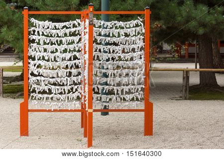 Kyoto Japan - September 15 2016: Vermilion rack with white paper prayer strips at Heian Shrine. People print or write their pleas and wishes on paper and leave it at the shrine.