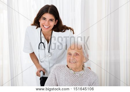 Portrait Of Happy Female Doctor With Handicapped Senior Patient In Hospital