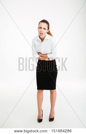 Full length portrait of a stressed businesswoman having stomach pain over white background