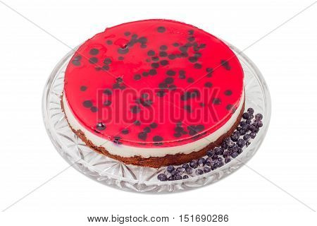 Layered cake with layers of sponge cake milk jelly berry jelly and separately frozen berries on a glass cake serving dish on a light background