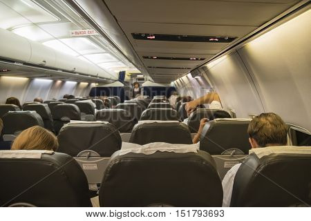 Interior of airplane with passengers on seats waiting to taik off at night.