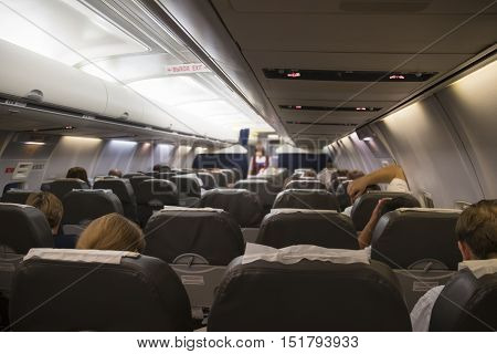 Interior of airplane with passengers on seats waiting to taik off at night.
