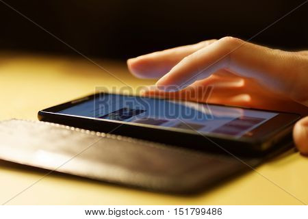 Human hand using smartphone. Finger swipe up and down the screen of smartphone. Warm light. Shallow focus.