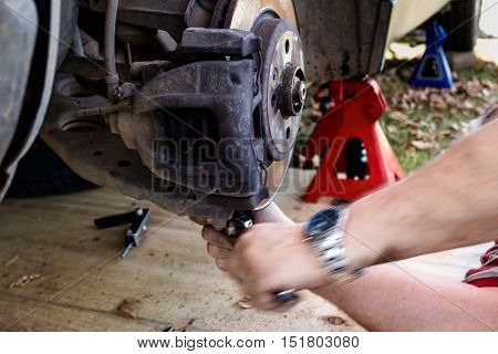 Motion blur of mechanic working on car wheel hub outside
