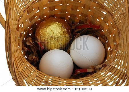 Eine goldene und zwei weiße Eier im Korb
