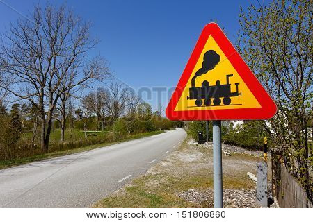 Swedish road sign Level crossing without gates or barriers ahead at the side of a narrow road.