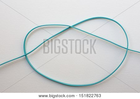 Heart-shaped tie of electric wire on white canvas background