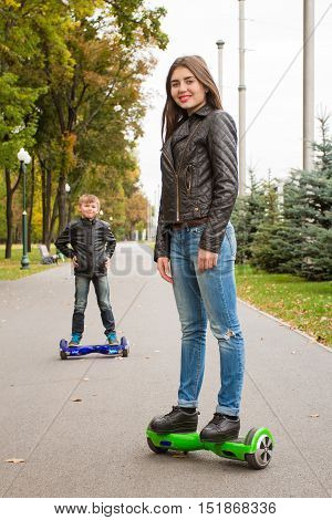 Young  Woman Riding Hoverboard - Electrical Scooter, Personal Eco Transport. On  Background Of  Boy