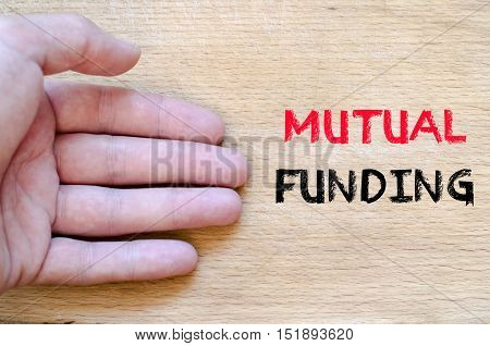 Human hand over wooden background and mutual funding text concept
