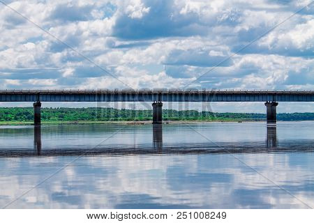 Steel Bridge With Lots Of Clouds In The Sky And Their Reflection In Water