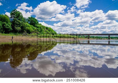 Steel Bridge With Lots Of Clouds In The Sky And Their Reflection In Water