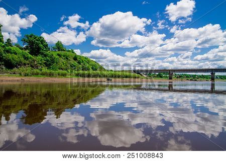 Steel Bridge With Lots Of Clouds In The Sky And Their Reflection In Water