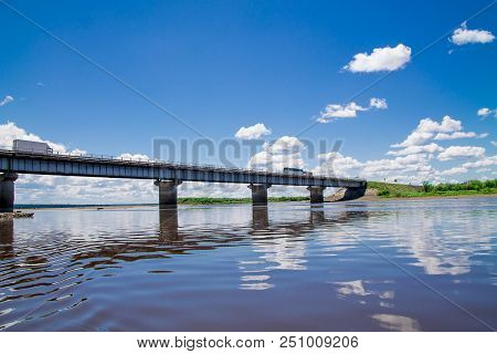Steel Bridge With Lots Of Clouds In The Sky And Their Reflection In Water