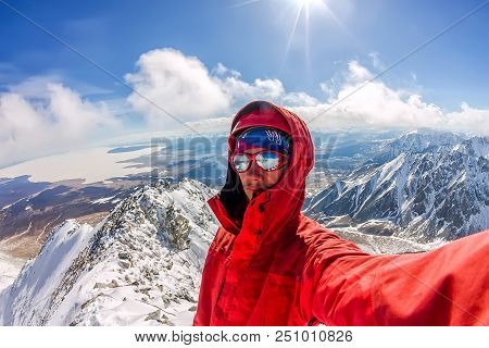Selfi Male Mountaineer In Snowy Mountains, Wearing A Helmet With A Backpack.