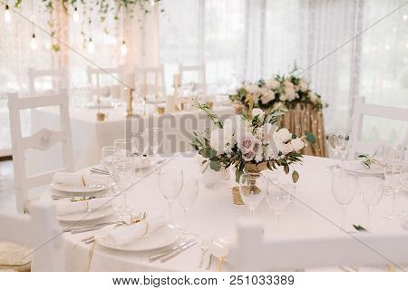 Round White Table With Graceful Compositions Of Fresh Flowers. A Decor Of Wedding Tables At Restaura