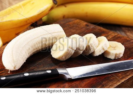 A Banch Of Bananas And A Sliced Banana Over A Table.
