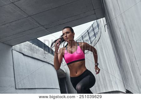 Towards A Healthier Lifestyle. Modern Young Woman In Sports Clothing Running While Exercising Outdoo