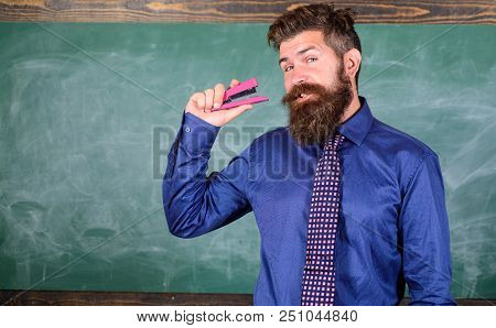 Man Bearded Teacher Or Educator In Formal Wear Holds Stapler Chalkboard Background. School Supplies 