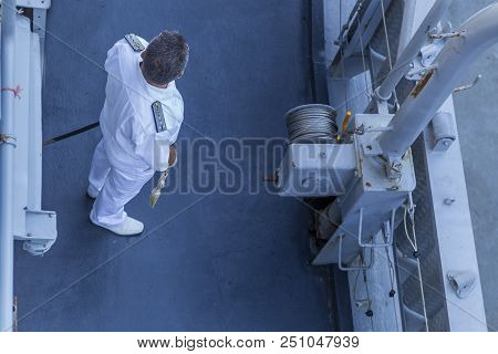 A Marine Officer In Uniform And A Hat Walking Along The Deck Of A Warship. Editorial Use Only. Burga