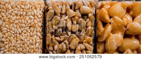 Kozinaki With Seeds, Nuts, Sesame And Honey. On A Dark Wooden Background. Long Wide Banner.