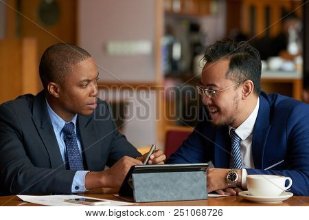 Cheerful Multi-enthic Business People Discussing Agenda At Meeting In Cafe