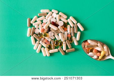 Many Colorful Pills With A Spoon On A Turquoise Background . The Concept Of A Healthy Lifestyle .