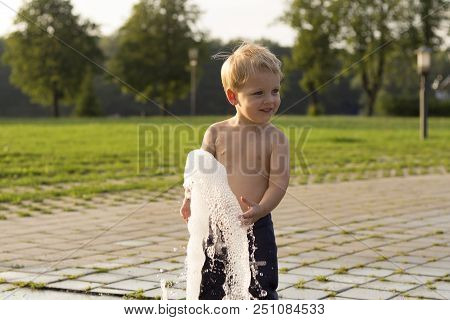 Cute Baby Boy Playing With Water Jet In Park Fountain.