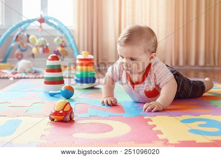Portrait Of Cute Adorable Blond Caucasian Smiling Child Boy With Blue Eyes Crawling On Floor In Kids