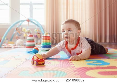 Portrait Of Cute Adorable Blond Caucasian Smiling Child Boy With Blue Eyes Crawling On Floor In Kids