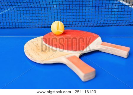 Pair Of Old Pingpong Rackets And A Ball On A Blue Pingpong Table