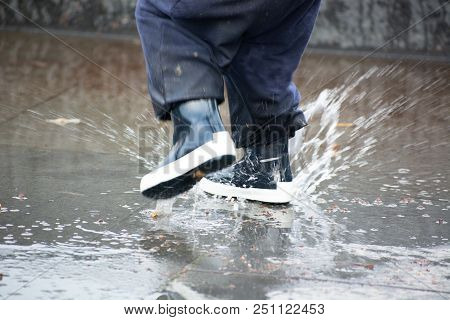 Close-up Of Kid Wearing Blue Rain Boots And Walking During Sleet, Rain And Snow On Cold Day