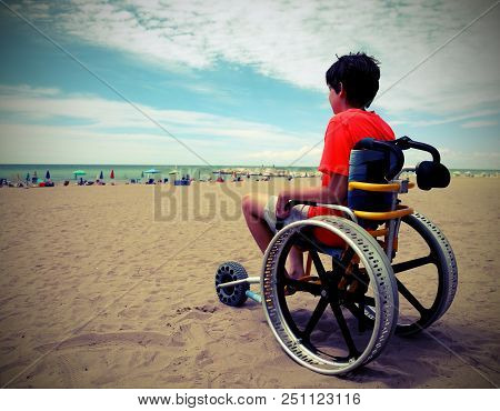 Young Boy With T-shirt Sitting On The Special Wheelchair With Aluminum Alloy Wheels With Vintage Eff