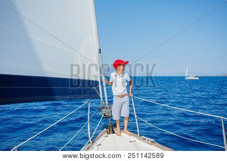 Cute Boy On Board Of Sailing Yacht On Summer Cruise. Travel Adventure, Yachting With Child On Family