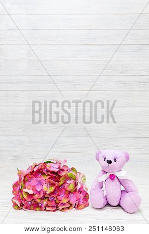 Hortense A Large Deciduous Chameleon And A Pink Bear Toy Against A Light Wood Background