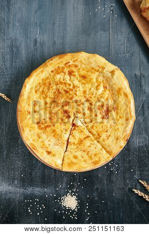 Megrelian Khachapuri Made From a Delicious Tender Dough with Melted Burnt Imeretian Cheese and Butter Close Up. Traditional Most Common Circular Hachapuri Topped with Lots of Grated Cheeses