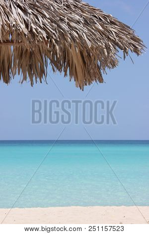 Dry Palm Leaves As Umbrella Near Turquoise Sea