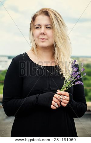Young Beautiful Woman In A Black Dress With A Bouquet Of Lavender