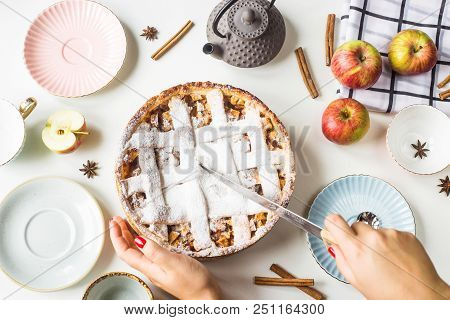 Homemade Apple Pie Sprinkled With Powdered Sugar In Female Hand On A White Table Next To Apples, Cin