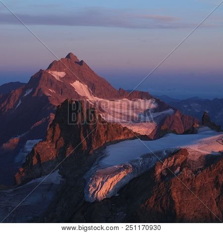 High Mountains In Purple Evening Light. Mount Fleckistock And Mount Stucklistock.