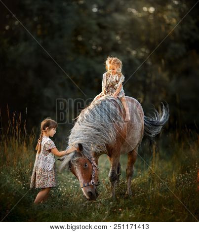 Little Sisters With Horse At Summer Cloudy Evening