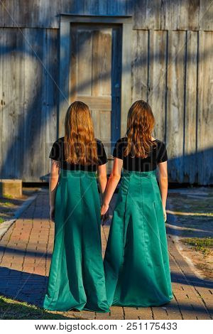 Long dress twin teen sisters hand in hand at the park sooden cabin