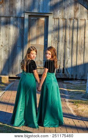 Long dress twin teen sisters hand in hand at the park sooden cabin