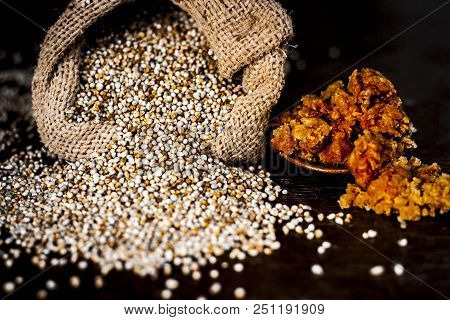 Close Up Of Raw  Dried Grains Of Pearl Millet With Jaggery Or Gud On A Wooden Surface In Drak Gothic