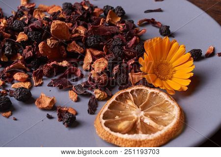 Black Dry Fruit Tea Leaves In Blue Plate On Wooden Table