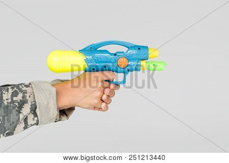 Partial View Of Boy In Camouflage Clothing With Toy Water Gun In Hands Isolated On Grey