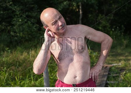 Mature European Man With Mustache Trying To Pull Water Out Of Ear After Swimming In Lake Or River. E