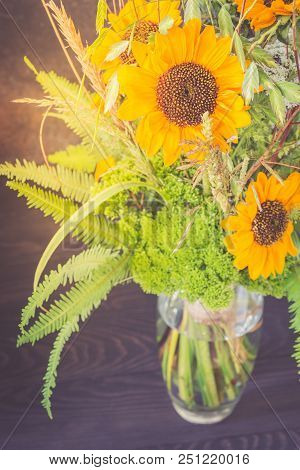 Bouquet Of Sunflowers In A Glass Vase On A Wooden Table. Retro Toned.