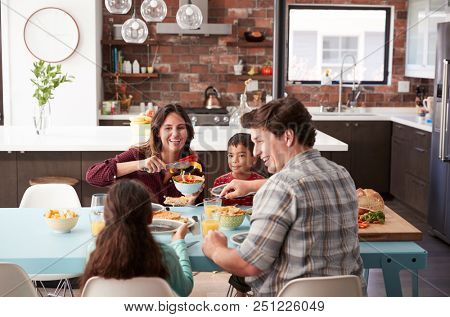 Family Enjoying Meal Around Table At Home Together