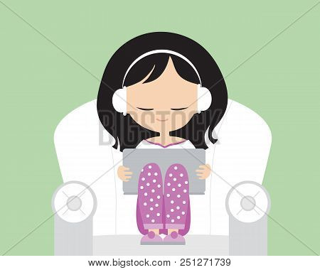 Young Woman With Headphones In Pink Pajamas On Armchair With Armrests, Holding Laptop And Listening 