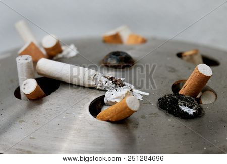 Burnt And Discarded Cigarettes On Street Litter Bin Top.
